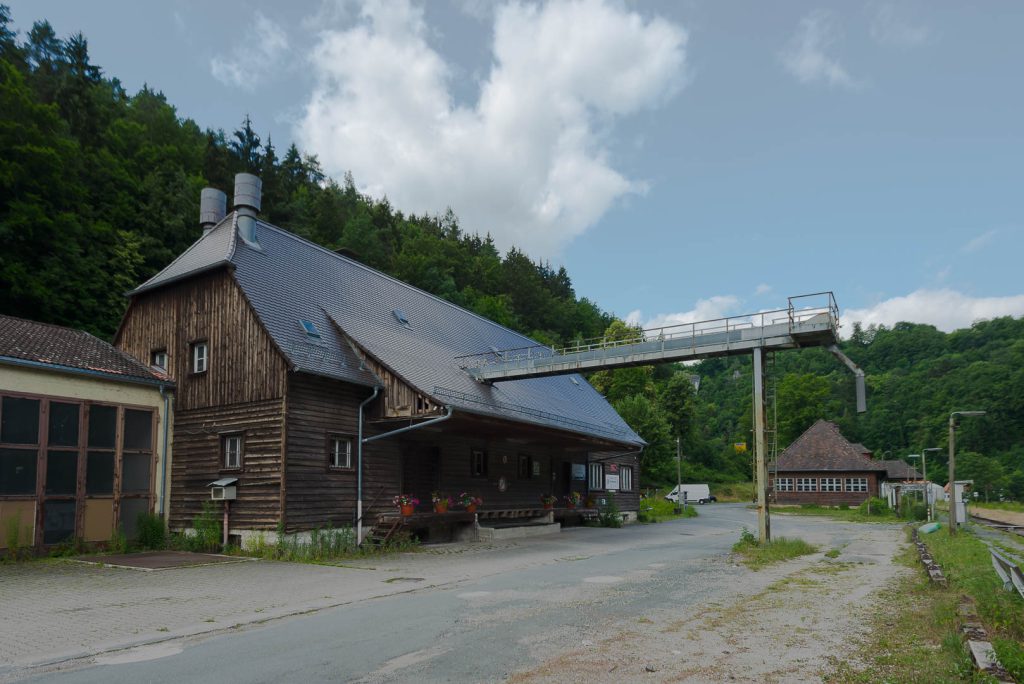 Außenansicht der historischen Lagerhalle der Baywa in Behringersmühle, mit dem Getreide-Förderer der über das ehemalige Ladegleis geht.